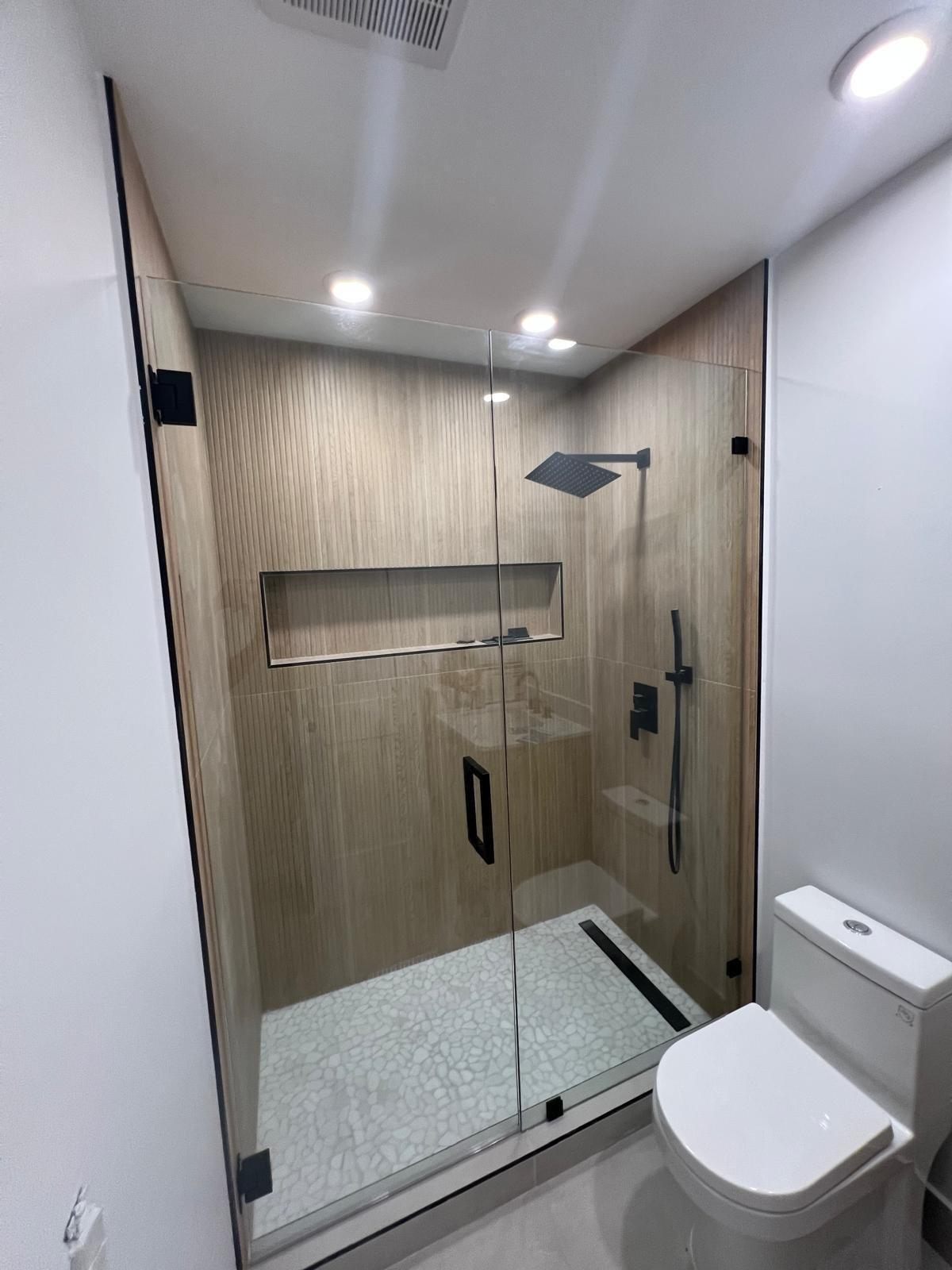 Ducha terminada con vidrio templado, porcelanato tipo madera y grifería negra