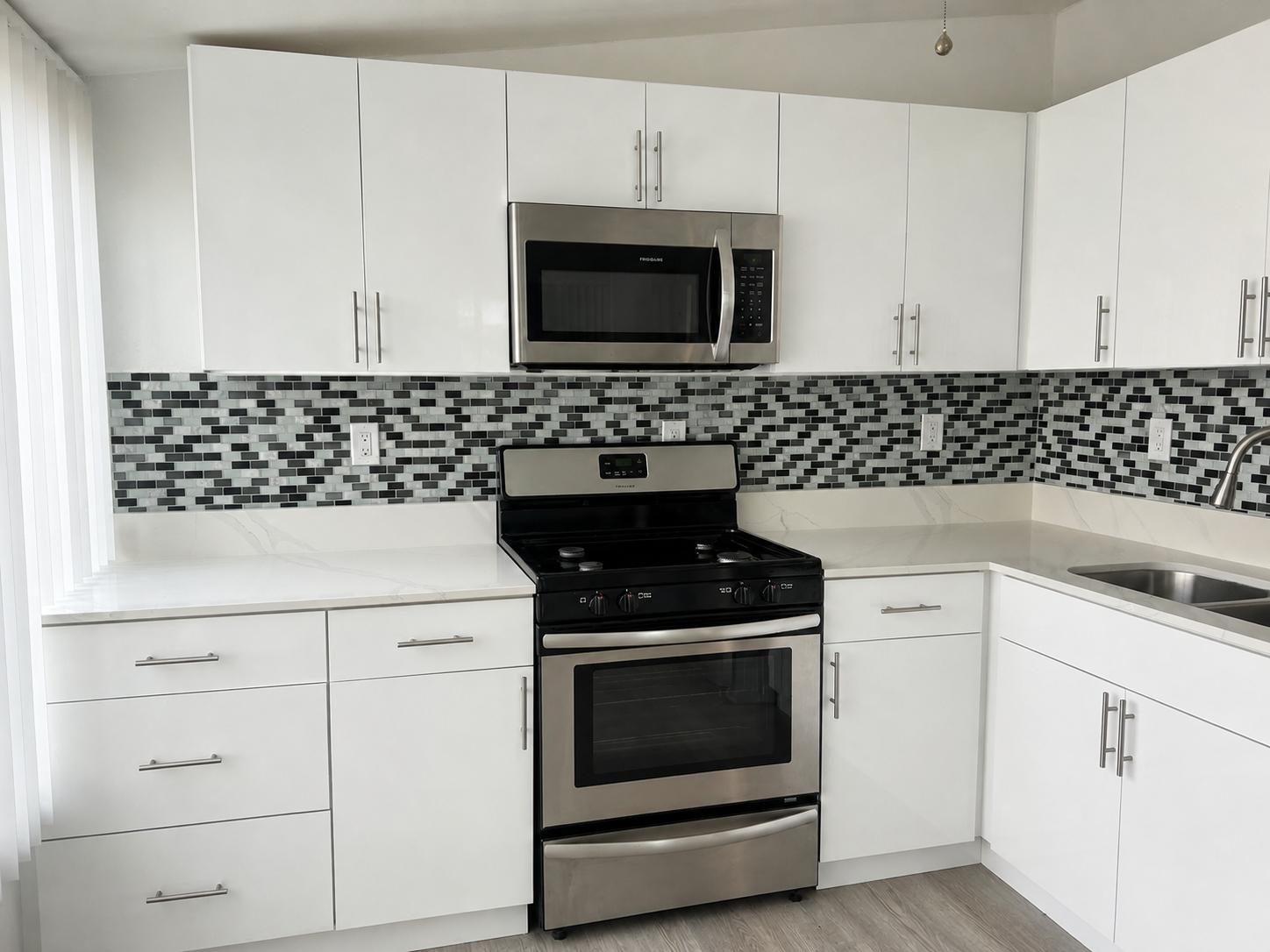 Cocina renovada con gabinetes blancos y encimera de mármol